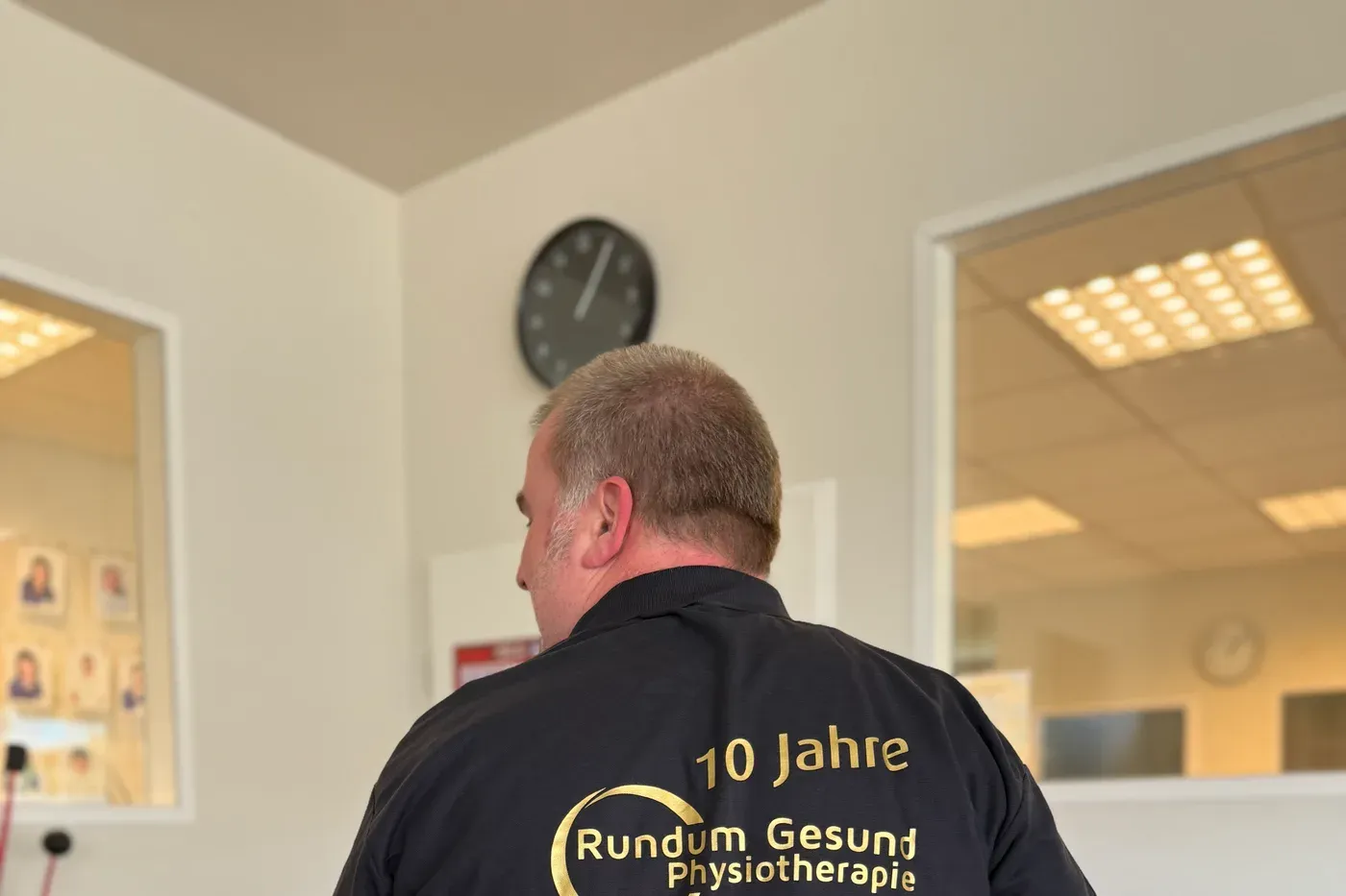 Poloshirt mit der goldenen Aufschrift „10 Jahre Rundum Gesund Physiotherapie" auf dem Rücken