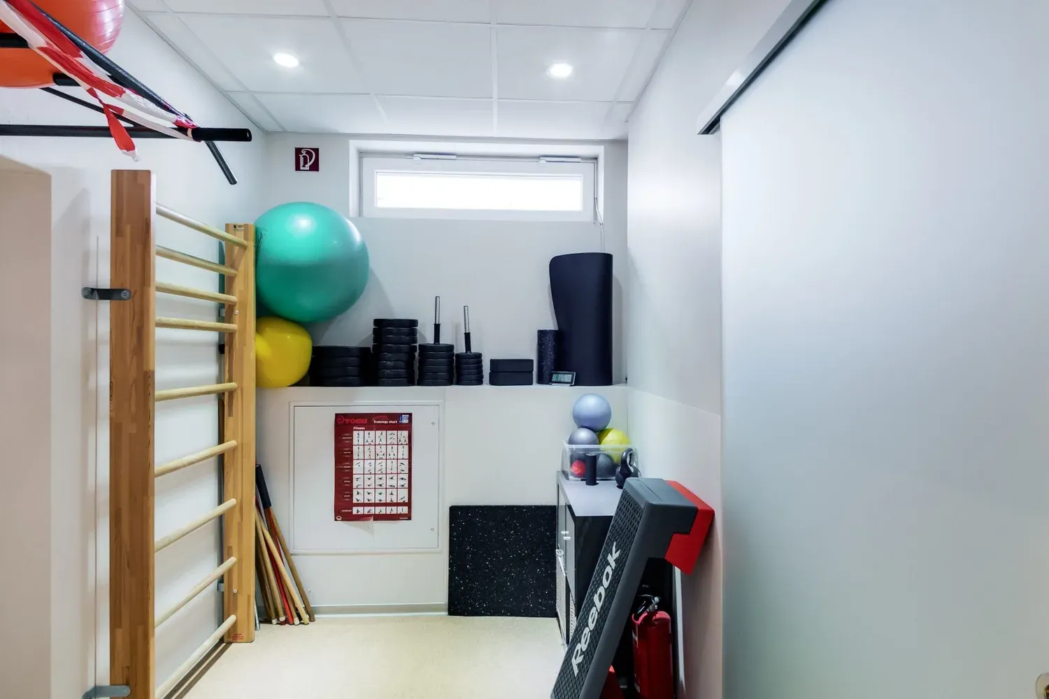 Sprossenwand mit Gymnastikbällen, Matten und Trainingsgeräten